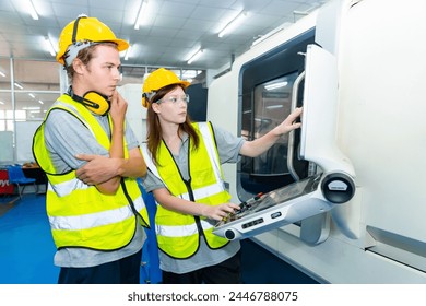 Manufacturing industry factory manufacturing technology concept. Caucasian man and woman engineer worker in safety wear working and maintaining control CNC lathe machine system in factory plant room.
