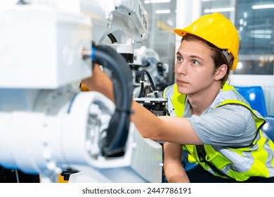 Manufacturing industry factory manufacturing technology concept. Professional male technician engineer in safety wear checking robotic machine arm system in production line for repair and maintenance. - Powered by Shutterstock