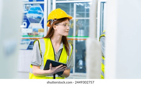 Manufacturing industry factory manufacturing technology concept. Caucasian woman engineer worker in safety wear working and maintaining control CNC lathe machine system screen in factory plant room.