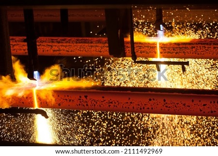 Manufacturing of mild steel square bar on continuous casting machine. Cutting bars by gas torch. Hot bright metal sparks.