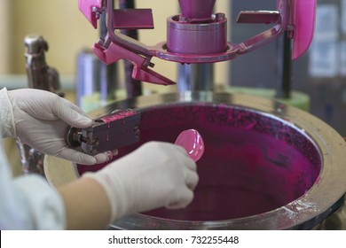 Manufacturing paint in a factory. Pink colored paint in an industrial environment. A lady wearing rubber gloves while working with liquids