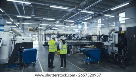Manufacturing Process Manager and Equipment Supervisor Having a Meeting on Factory Floor, Discussing Production Technology, Strategic Business Partnerships, Metal Component Delivery Techniques