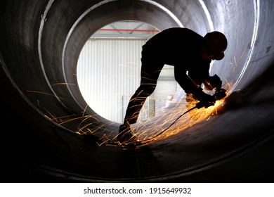 Manufacturing of steel pipes in one of the plant's workshops. Rotation of the angle grinder disc during operation. Bright sparks from metal cutting. Preparation of metal structures before welding.
