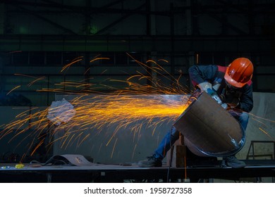 Manufacturing of steel pipes in one of the plant's workshops. Rotation of the angle grinder disc during operation. Bright sparks from metal cutting. Preparation of metal structures before welding.
