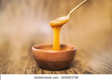 Manuka Honey Spoon Dipped In Golden Liquid Natural Superfood On Wooden Background.