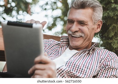 So Many Apps To Make Life Easier. Shot Of An Older Man Using A Digital Tablet During A Leisurely Break Outdoors.