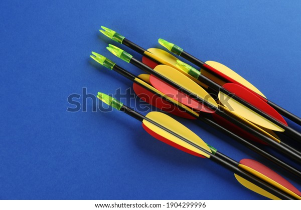 Many arrows on blue background, flat lay.\
Archery sport equipment