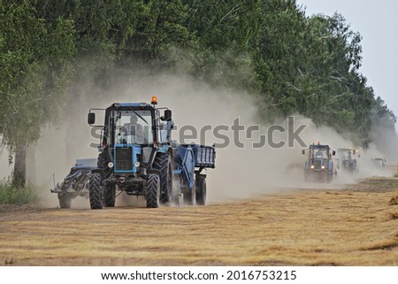 A many Belarus tractor harvester fast drive on dusty road on harvested linen field edge, linum harvesting in Europe at summer day