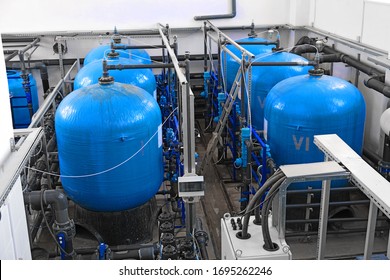 many big blue water tanks inside wastewater treatment facility, industrial interior inside, water factory