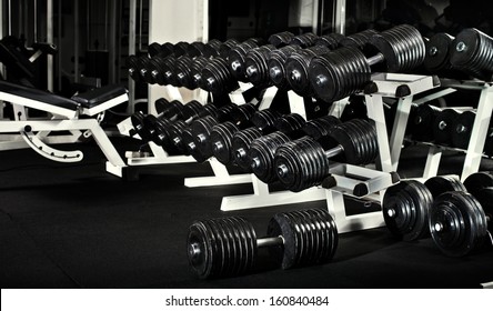 Many Black Dumbbells In Dark Weight Room, Horizontal Photo