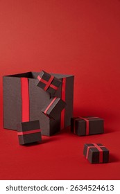 Many black gift boxes of different sizes are decorated on a bright red background. Take black friday theme photos, stimulate shopping interest, discount items