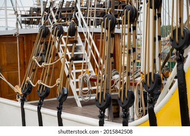 Many black pulleys with ropes on a large sailboat.