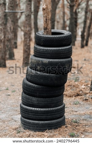 Many black round old used black car tires are put on a tree trunk in the forest in a row. Photography, concept.