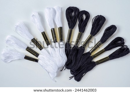 Many  black and white skeins of mouline thread for embroidery on a row in circle on whitebackground