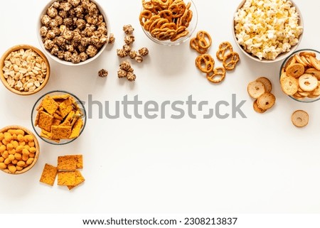 Many bowls with different salty snacks - chips pretzels nuts.