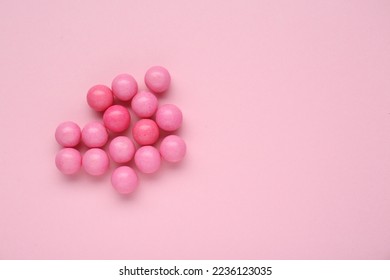 Many bright chewy gumballs on pink background, flat lay. Space for text
