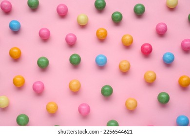 Many bright chewy gumballs on pink background, flat lay