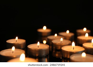 Many burning tealight candles on black background, closeup - Powered by Shutterstock