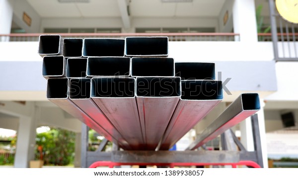 Many carbon steel\
rectangular tubes on top of pick up car with blurred background in\
convenient longer materials transmission in transport concept,\
focus on foreground 