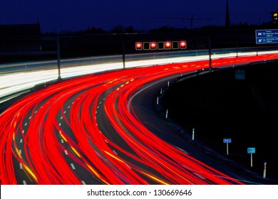many cars are driving at night on a highway and create light trails.