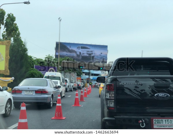Many cars line up to pay\
for the expressway or tollway area,has red and white witches\
plastic hat or cone traffic sign,placed on the road to divide the\
lane for motor\
vehicles,Bangkok,Thailand,2019.