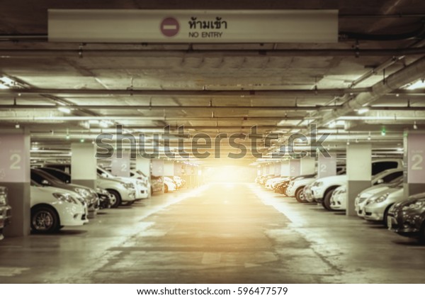 Many cars in parking garage interior,\
industrial building. Vintage filter\
effect.