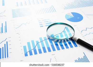 Many Charts And Magnifying Glass. Reviewing Data. Financial Reports And Magnifying Glass. Reflection Background.
