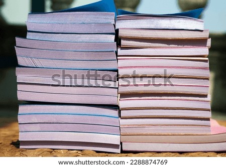 Many cheap small notepads in 2 stacks seen from a side. A pile of blue and pink scratchpads stacked on the floor
