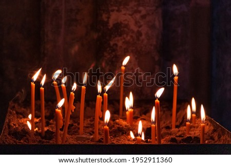 many church candles of varying degrees of combustion, stuck in the sand in the dark. selective focus. dripping wax from candle.