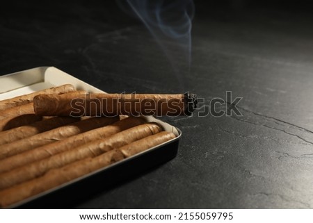 Many cigars in box on black table, closeup