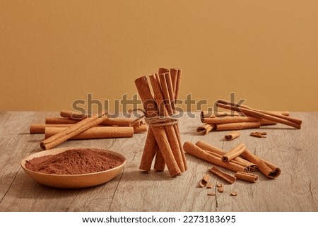 Many cinnamon sticks are decorated on a wooden table with cinnamon powder placed on a dish. Cinnamon (Cinnamomum) brings a lot of benefits for health, body and skin