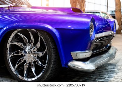 Many classic purple vintage old american cars parked in row at garage, exhibition of fest. Close-up detail view beautiful retro oldtimer vehicle hood, headlight, fender and shine chrome plated bumper