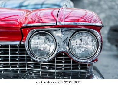 Many classic red vintage old american cars parked in row at garage, exhibition of fest. Close-up detail view beautiful retro oldtimer vehicle hood, headlight, fender and shine chrome plated bumper