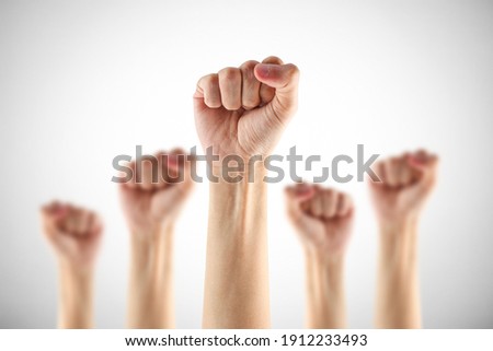 Many clenched fists punch air energetically on gray background. 
Together we stand ! 