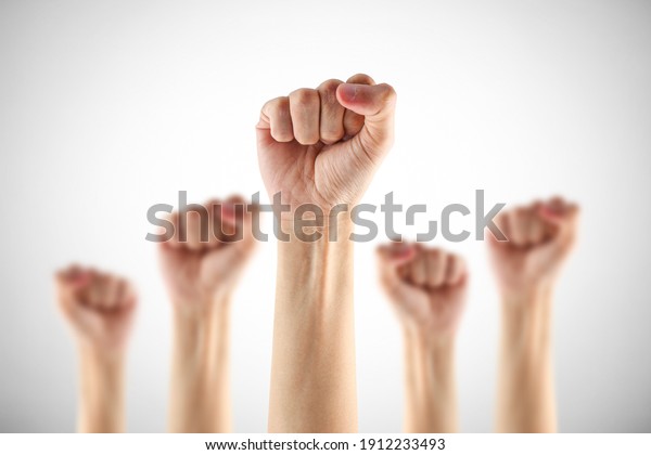 Many clenched fists punch air\
energetically on gray background. \
Together we stand !\
