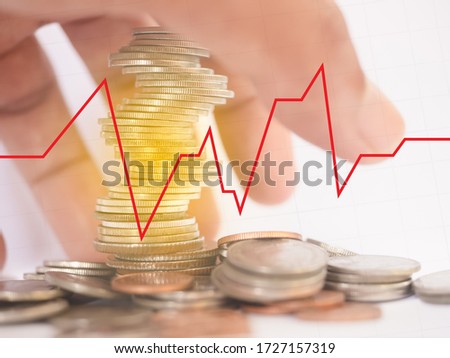 Many coins are stacked up. There is spread beside And with the hands of people going to catch the white background with a red line graph Blackline grid concept finance, investment, COVID-19 effects