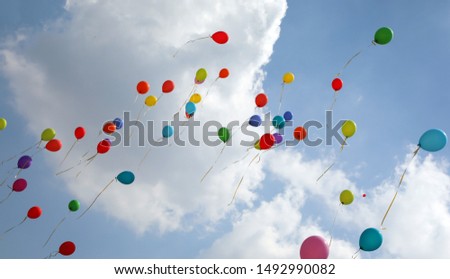 Many colored balloons fly into the blue sky with many white clouds in summer during the party