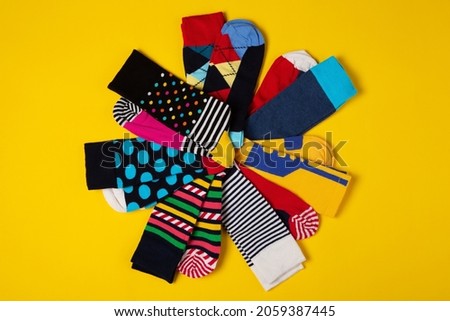 many colored socks with different patterns, laid out radially in the shape of a flower, on a yellow background, concept, copy space