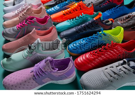 many colored sports shoes, sneakers and football boots, stand in a row, side location