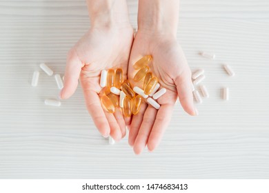 Many Colorful Capsules Of Tablets, Vitamins, Dietary Supplements In Hand On A White Table Close-up. Toning.