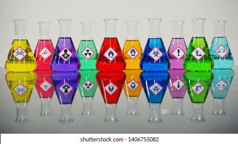 Many of colorful chemicals on Erlenmeyer flask with Variety type of chemical hazard warning symbols labels on.