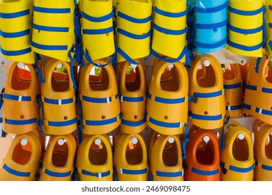 Many colorful soft kids life jackets in a row for water safety.
