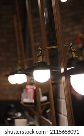 Many Copper Lamp Sconce Hanging From White Tile Wall Near Big Mirrors In Beauty Salon.