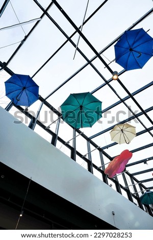 Many couloured umbrellas under glass roof in shopping centre. February, Stockholm, Sweden. February 2023.