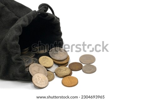 Many currency old coins in black cloth wallet bag on white background.