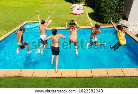 Many cute children jump into the swimming pool about to dive view from above