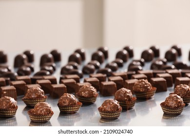 Many Delicious Chocolate Candies On Grey Table. Production Line