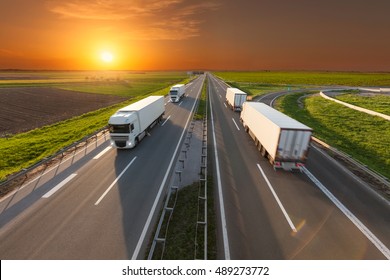 Many delivery trucks driving through agricultural fields. Fast blurred motion drive on the freeway at beautiful sunset. Freight scene on the motorway near Belgrade, Serbia.