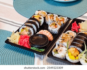 Many different colorful sushi rolls with soy sauce, wasabi, ginger and garnishes in a black tray on a decorative table setting, home dining food order concept, Japanese cuisine concept, lots of sushi - Powered by Shutterstock