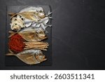 Many different dried fish snacks on black table, top view. Space for text